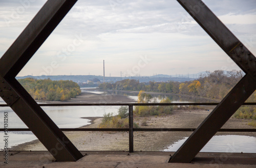 Top view onto dried out parts of the river Rhine through the steel girders (rhombus, cross) of a crossing railway bridge