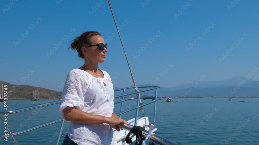 Female resting on the nose of ship. A happy woman in sunglasses enjoy the sea view from the yacht. A concept of summer sea trip during holidays. Female resting on the nose of ship. A happy woman in sunglasses enjoy the sea view from the yacht. A concept of summer sea trip during holidays.