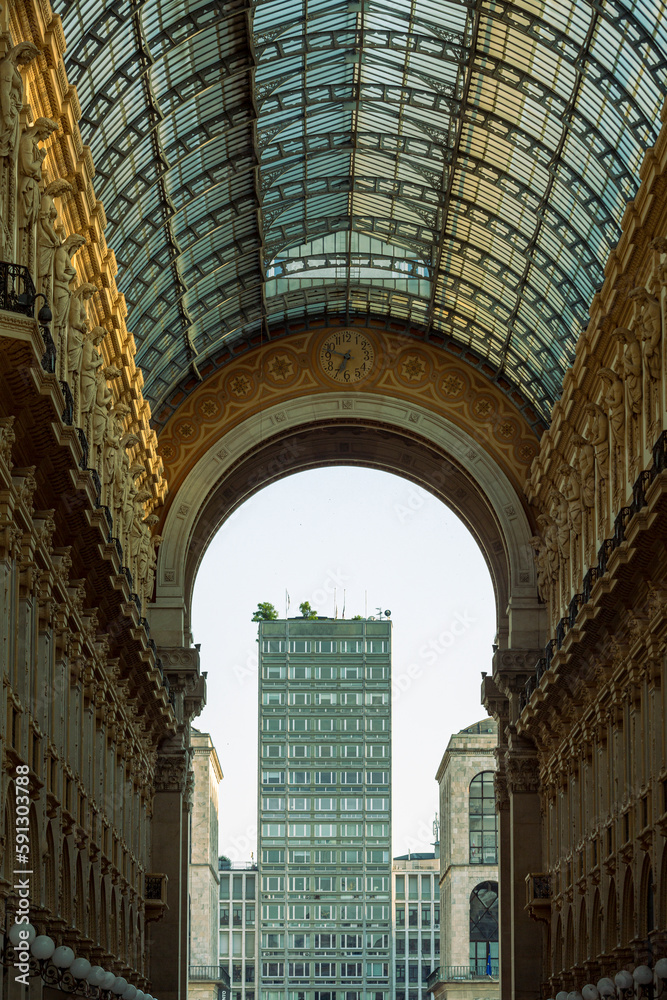 A building with a glass roof is visible through a tunnel that has a glass roof.