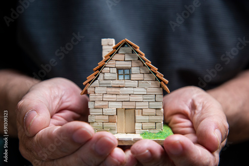 Photos Manos que sostienen una casa en miniatura hecha de ladrillos