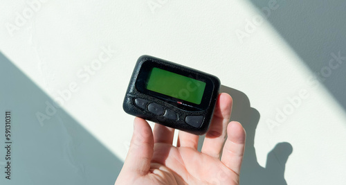 Pager is a small wireless device that receives and displays numeric or text messages, symbolizing the era of technological advancements in communication and transition from analog to digital device photo