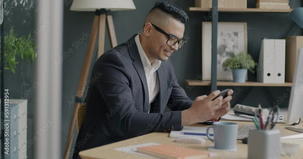 Portrait of Middle Eastern businessman playing video game using smartphone application relaxing in office. People and technology concept. Portrait of Middle Eastern businessman playing video game using smartphone application relaxing in office. People and technology concept.