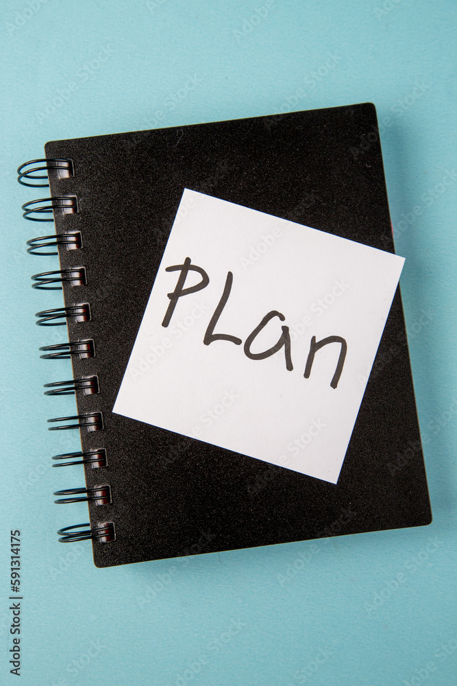 top view black copybook with plan written sticker on blue background