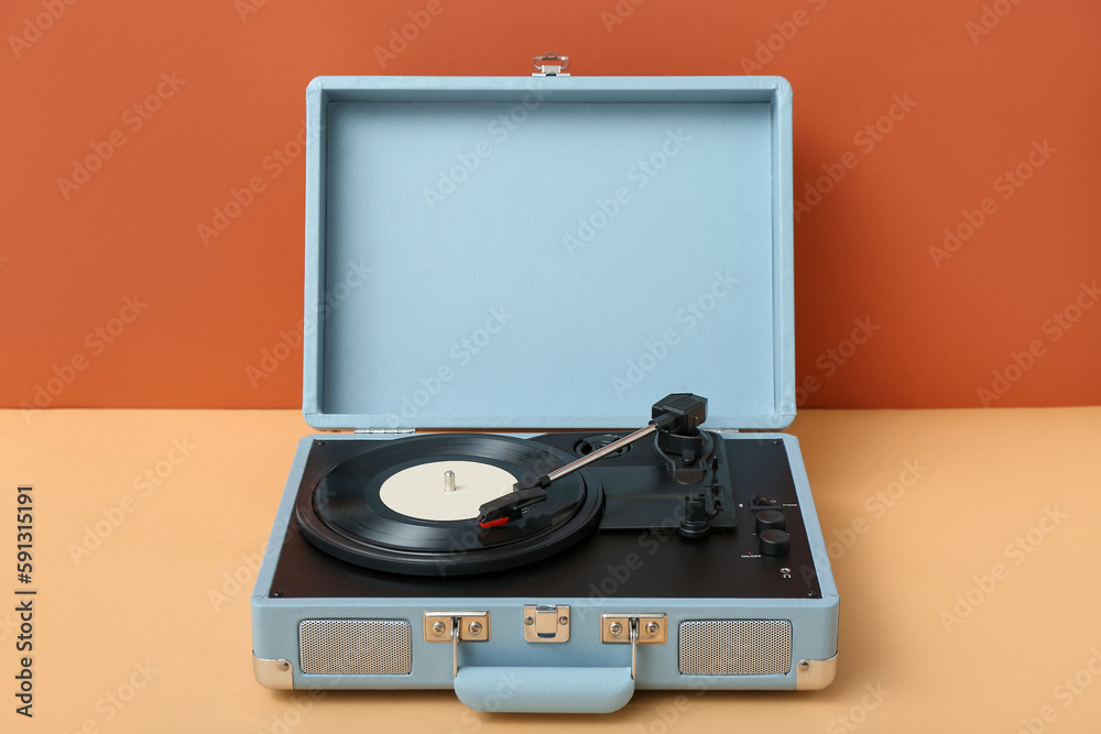 Fototapeta premium Record player with vinyl disk on table near orange wall