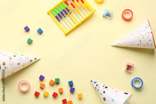 Frame made of toys and party hats on yellow background. Children's Day celebration