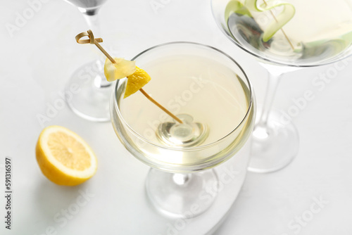 Glasses of tasty martini and lemon on white table