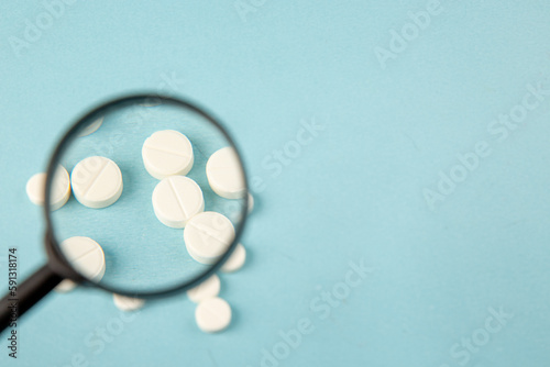 top view curing pills under magnifier on blue background lab disease covid- isolation pandemic virus health color