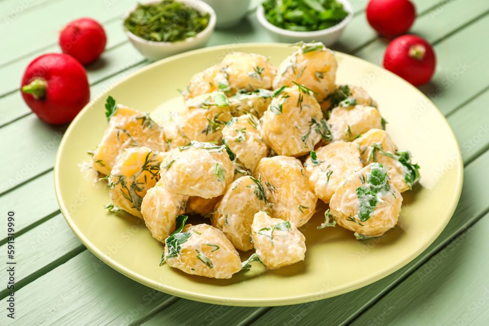 Plate of tasty Potato Salad with dill and parsley on green wooden background Plate of tasty Potato Salad with dill and parsley on green wooden background