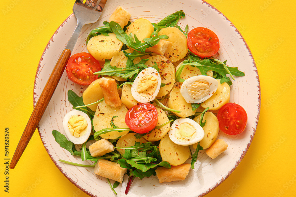 Plate of tasty potato salad with eggs and tomatoes on yellow background, top view Plate of tasty potato salad with eggs and tomatoes on yellow background, top view