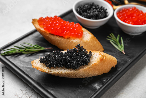 Tasty bruschettas with red and black caviar on light background