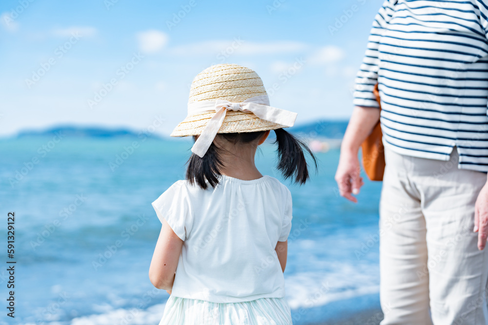 海辺を散歩する子供と家族