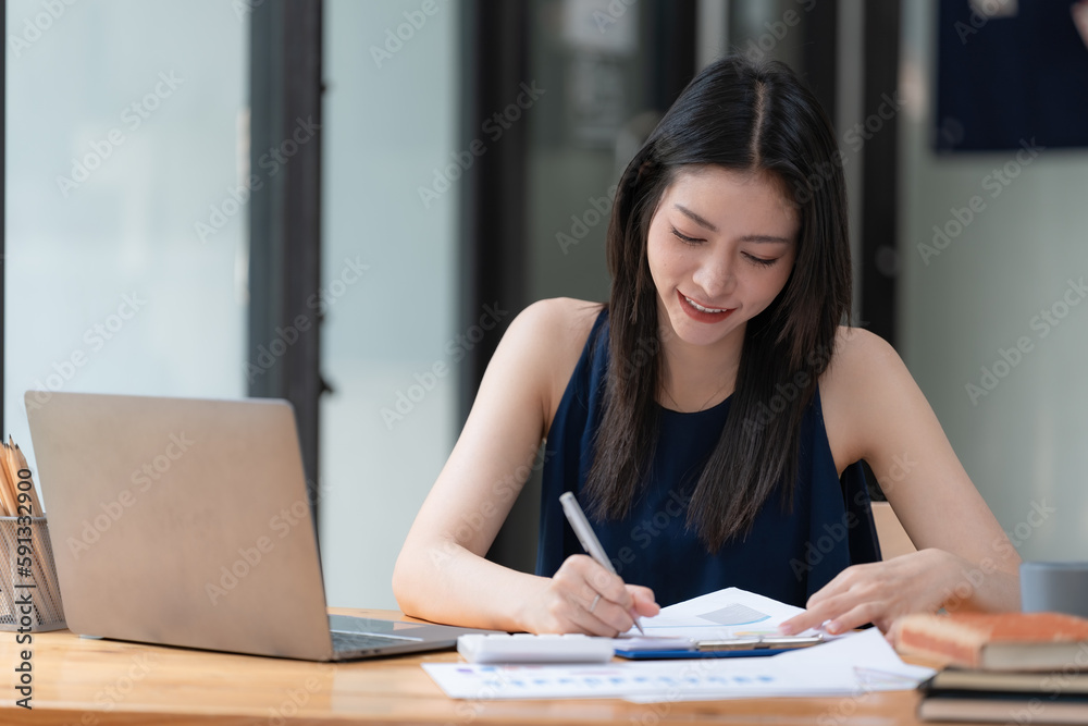 Portrait of a businesswoman with a laptop writing on a document at her office. Portrait of a businesswoman with a laptop writing on a document at her office.