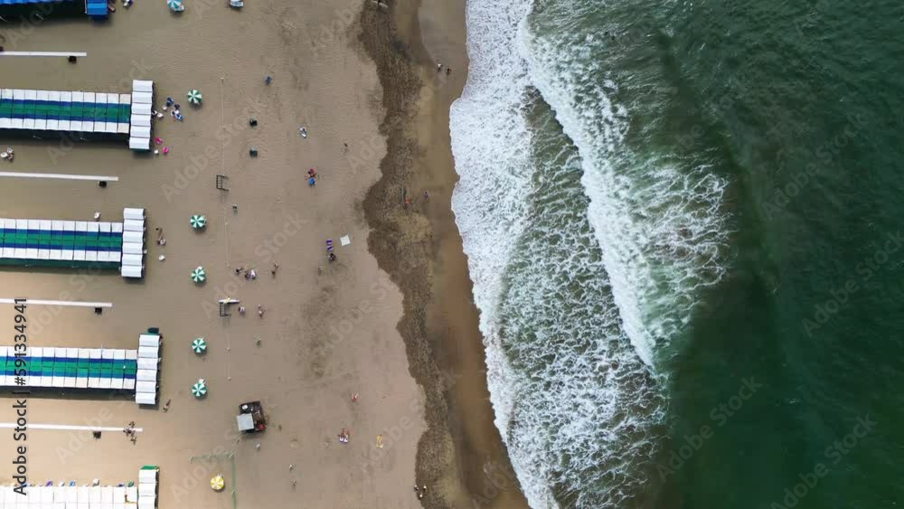 Aerial view of Miramar beach, waves breaking, people walking. Drone shot moving top-down view Aerial view of Miramar beach, waves breaking, people walking. Drone shot moving top-down view