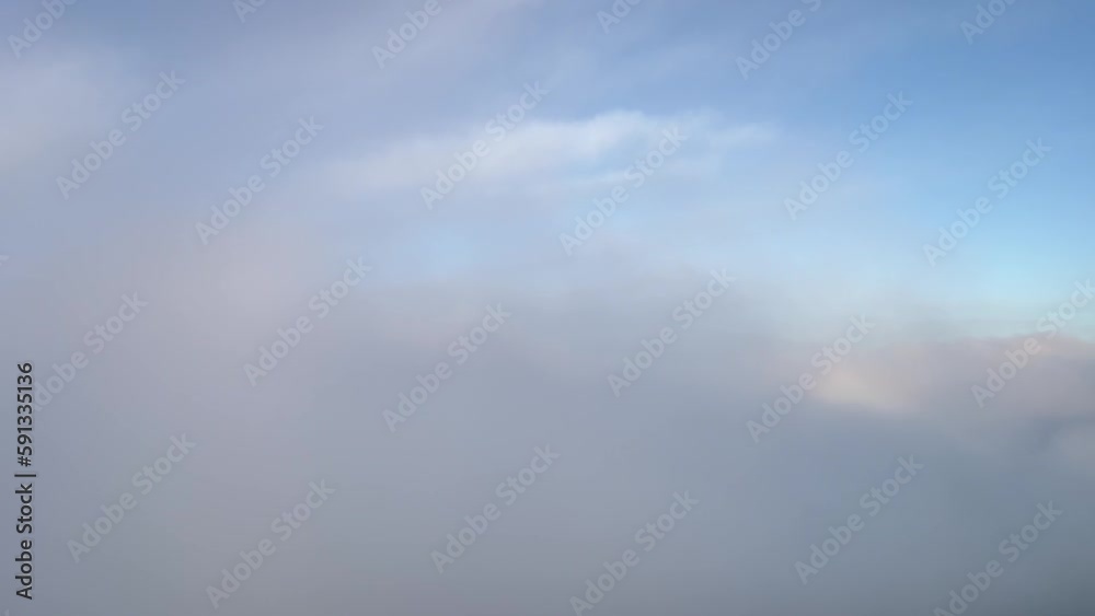 A pilot’s perspective: Airplane flying just above the clouds with the halo of the plane ahead. Daylight.