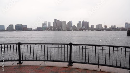 Boston skyline and boats from Piers Park Donald McKay Memorial with fence in slow motion on a cool fall day by the water photo