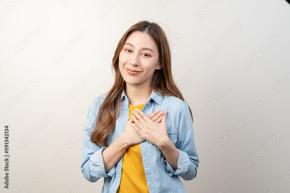 Young woman hold hands touching her heart feeling thankful isolated on background. Young woman hold hands touching her heart feeling thankful isolated on background.