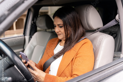 Mature female driver using smartphone, setting up navigator on mobile app, sitting in driver's seat