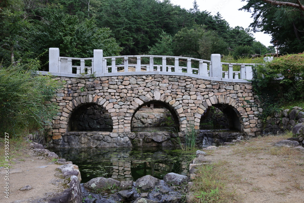 a small lake and a white wall stone bridge