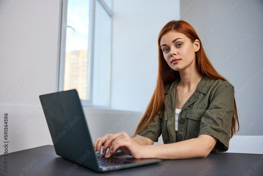 pensive redhead woman sitting at laptop while working in office pensive redhead woman sitting at laptop while working in office