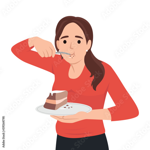 Hungry young woman eating cake suffer from eating disorder. Happy girl enjoy chocolate dessert. Guilty pleasure