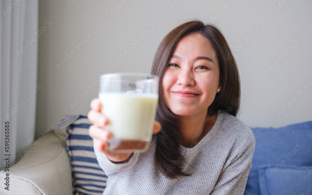 Portrait image of a young woman holding and showing a glass of fresh milk Portrait image of a young woman holding and showing a glass of fresh milk