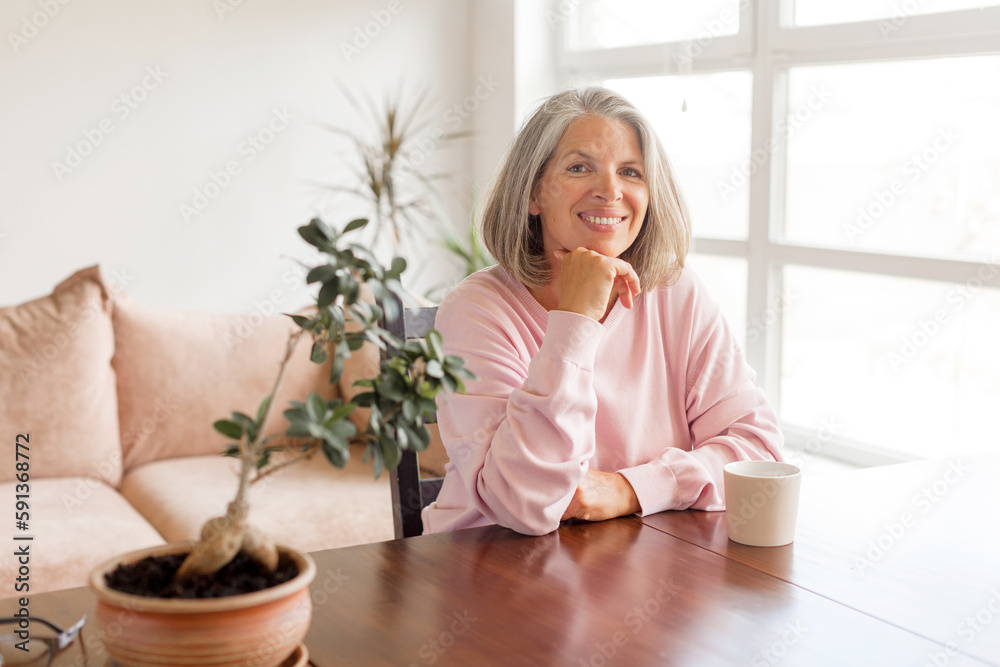 Calm and peaceful middle-aged gray-haired woman takes a break at home