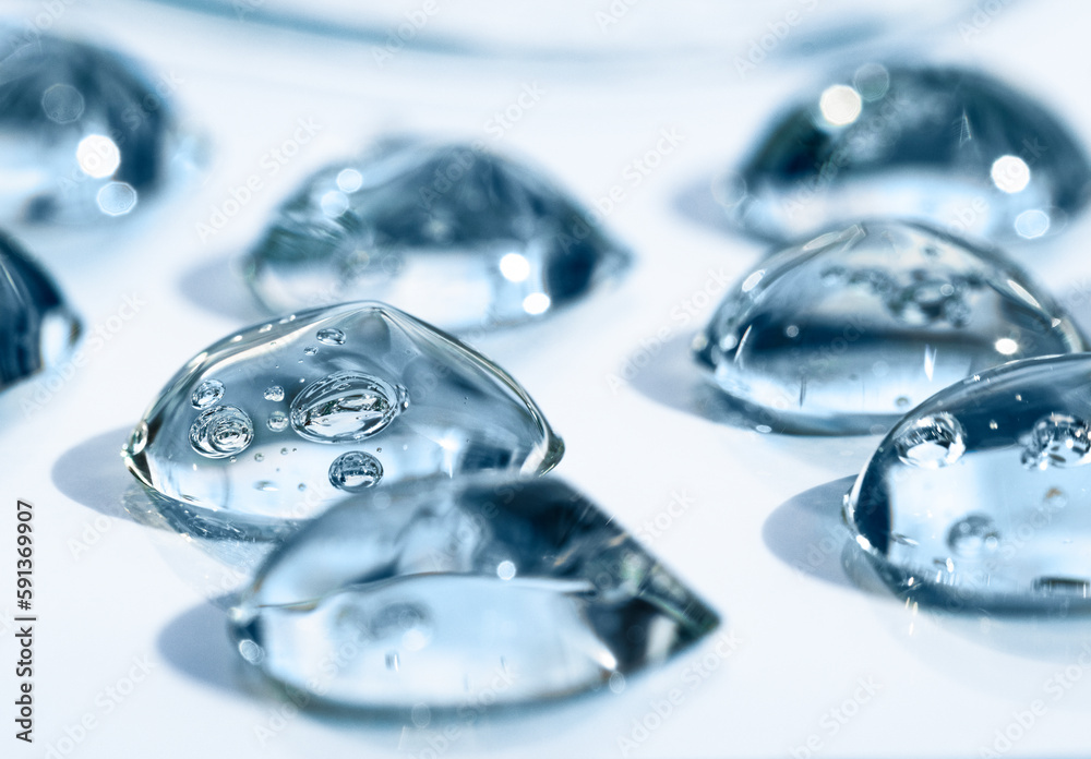 Drops of hyaluronic acid with bubbles front view, macro. Cosmetic texture on a blue background, liquid, transparent product. Drops of hyaluronic acid with bubbles front view, macro. Cosmetic texture on a blue background, liquid, transparent product.