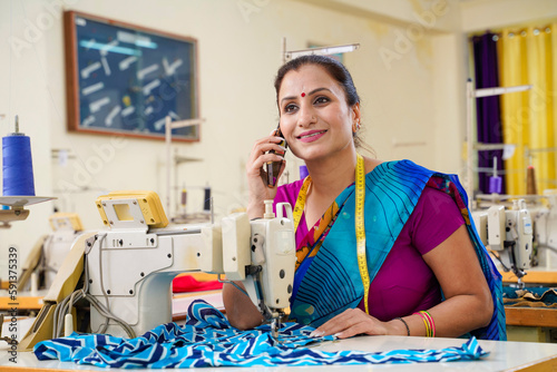 Indian woman talking on smartphone while working at textile factory.