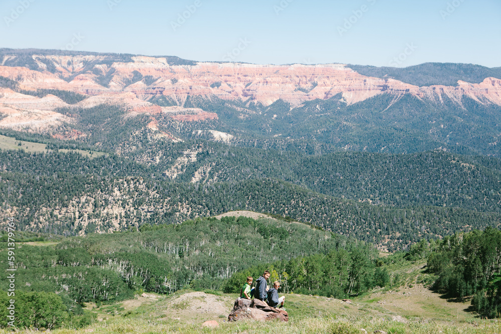 Boys sitting on a rock with forest and mountains on hike