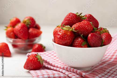 Fresh ripe strawberries in a bowl on a white texture background.