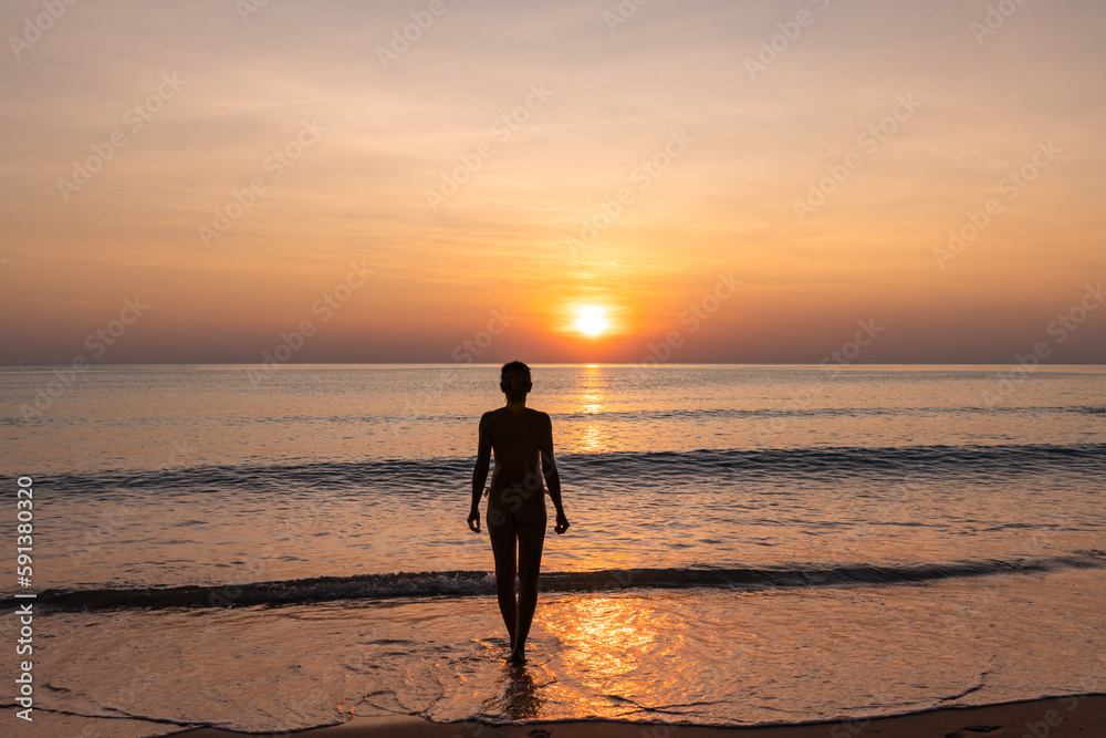 Silhouette of woman in an orange sunset on the beach