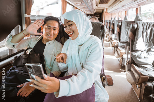 muslim couple using phone while travel by bus during eid mubarak holiday to meet family at home