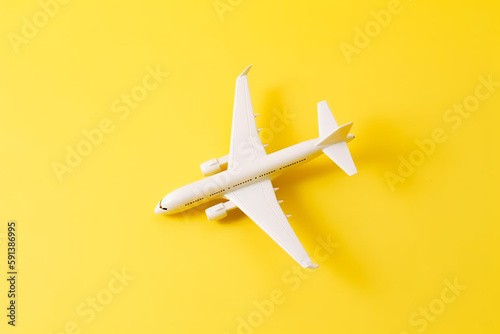 Travel style of flat lay design featuring white plane on vibrant yellow background. Generative AI