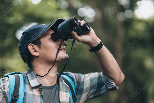 Hikers use binocular to see animals and view landscape with backpacks in the forest. hiking and adventure concept.