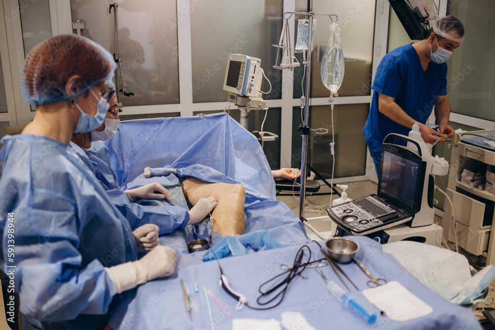 The surgeon performs the operation on the legs with the help of innovative technologies - laser. Treatment of varicose veins promptly, close up. A phlebologist treats a patient. The surgeon performs the operation on the legs with the help of innovative technologies - laser. Treatment of varicose veins promptly, close up. A phlebologist treats a patient.