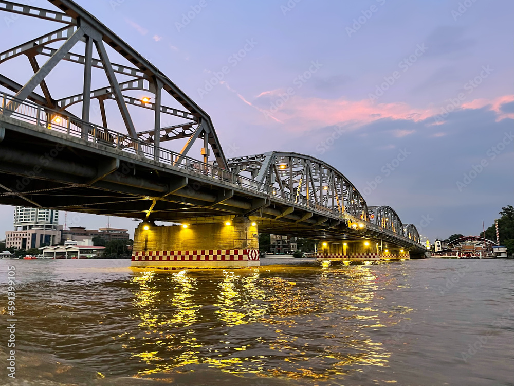 Krung Thon Bridge against the backdrop of a beautiful pink sunset in the sky with clouds. Evening illumination reflected on the water surface of Chao Phraya River. Sang Hi Bridge. Bangkok. Thailand.