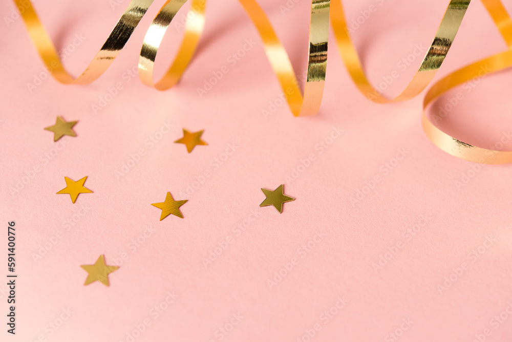 Golden stars of confetti and ribbon on pink background. Brilliant sequins. Holiday greeting card. happy holidays. Minimal, flat lay, copy space