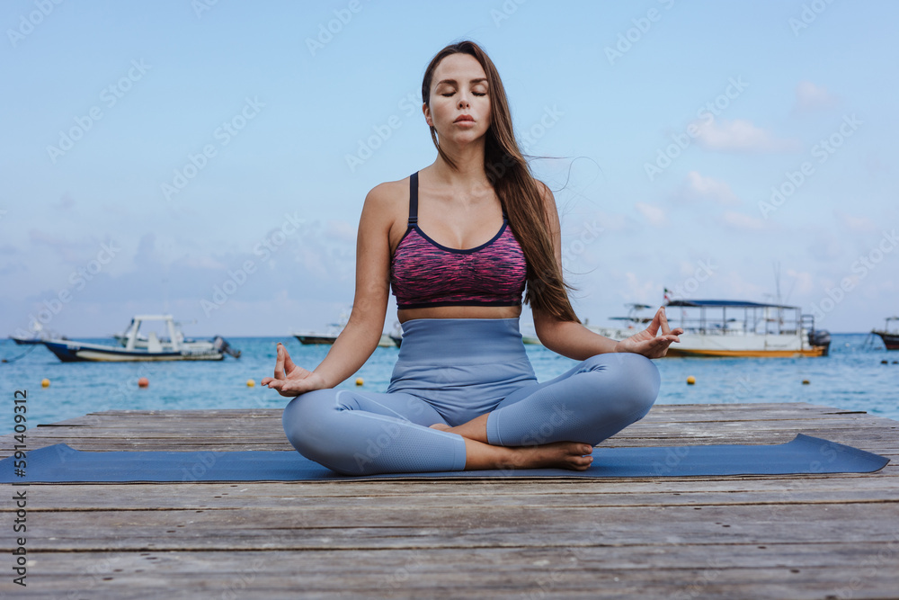 Young latin woman meditating on the beach pier or dock at the seaside in Mexico Latin America, hispanic female
