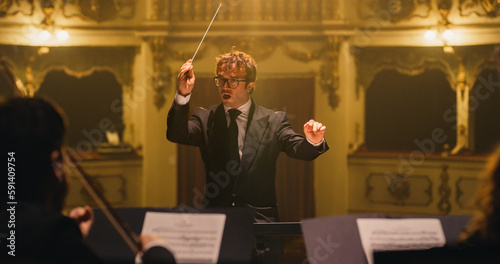 Canvas-taulu Cinematic Close Up of Conductor Directing Symphony Orchestra with Performers Playing on Stage During Music Concert