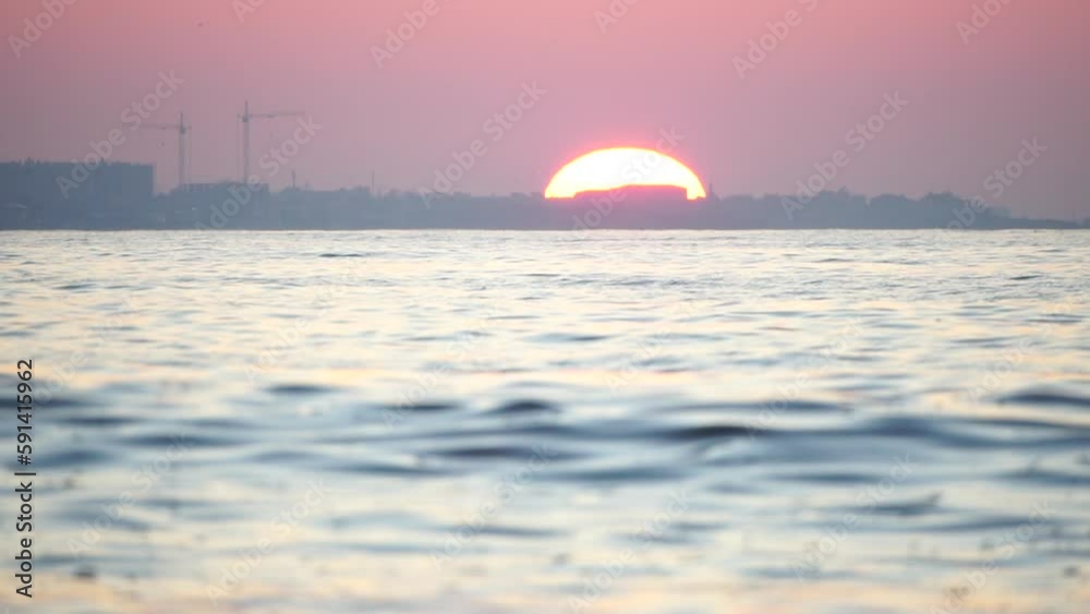 Sunset sea and silhouette of resort town located on the seashore with red sunset sun behind. Holiday recreation concept. Abstract nautical summer ocean sunset nature background. Sunset sea and silhouette of resort town located on the seashore with red sunset sun behind. Holiday recreation concept. Abstract nautical summer ocean sunset nature background.