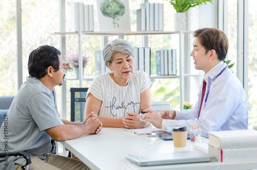 Asian professional successful male doctor in white lab coat with stethoscope hold medicine pill bottle showing explaining dosage and usage to elderly old senior patient and cousin in hospital office