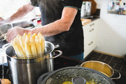 old man cooking asparagus in the kitchen