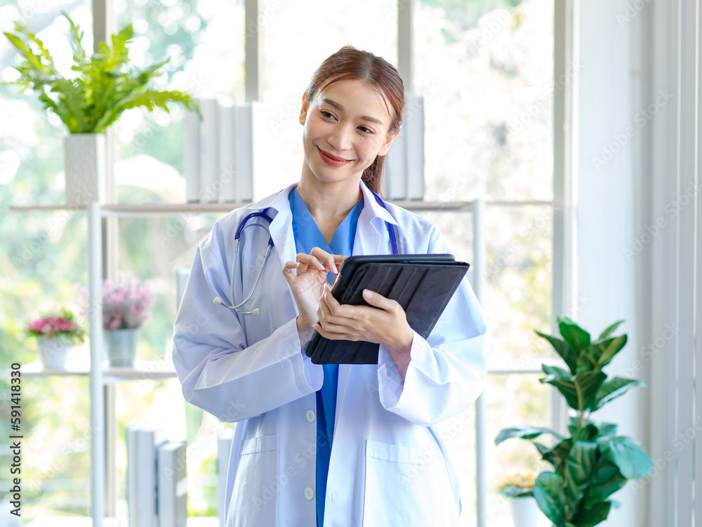 Asian professional successful female doctor in white lab coat with stethoscope standing smiling holding tablet computer posing in hospital office hall way. Asian professional successful female doctor in white lab coat with stethoscope standing smiling holding tablet computer posing in hospital office hall way.