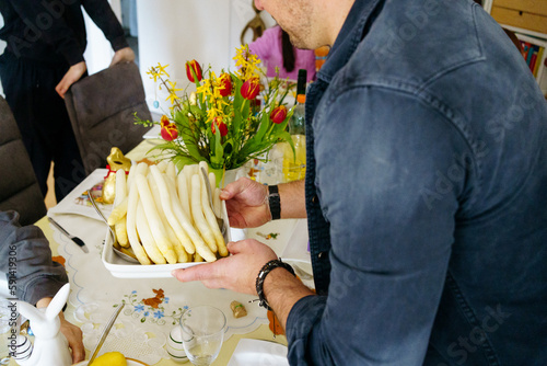 The man serves white asparagus on the table