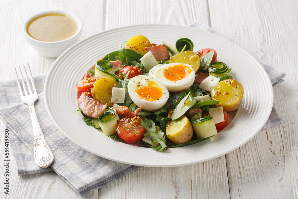 Farm salad with potatoes, tomatoes, bacon, arugula, zucchini, cheese and soft-boiled eggs seasoned with vinaigrette sauce close-up on a plate on the table. Horizontal Farm salad with potatoes, tomatoes, bacon, arugula, zucchini, cheese and soft-boiled eggs seasoned with vinaigrette sauce close-up on a plate on the table. Horizontal