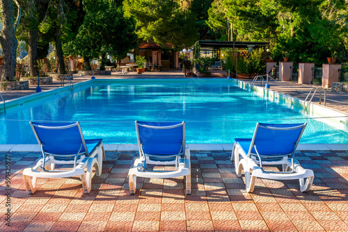 blue lounge chair in a hotel with water and swimming pool on background , vacation resort landscape of a beautiful place for holiday relax