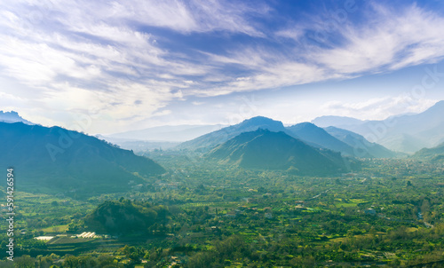 landscape of green summer highland mountain range with green beautiful valley below and amazing blue cloudy sky