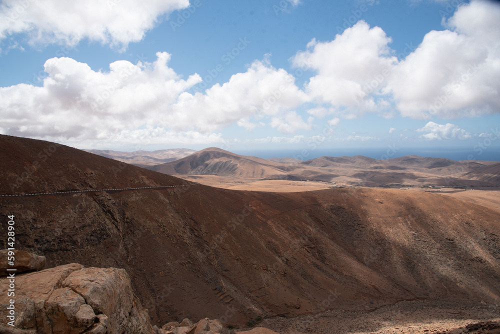 Vista panorámica de un impresionante paisaje montañoso y desértico con grandes montañas volcánicas inactivas y el mar de fondo en un día soleado en Fuerteventura, Islas Canarias.