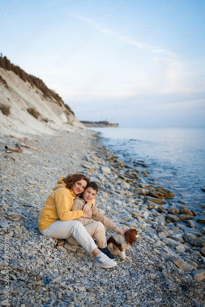 Naklejka premium family walk on the seashore in the cold season. happy mother and son hugging each other