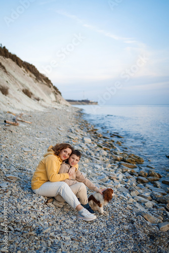 family walk on the seashore in the cold season. happy mother and son hugging each other